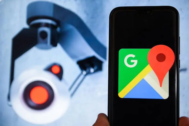 a hand holding a phone with Google Map opened on the screen and a cctv camera